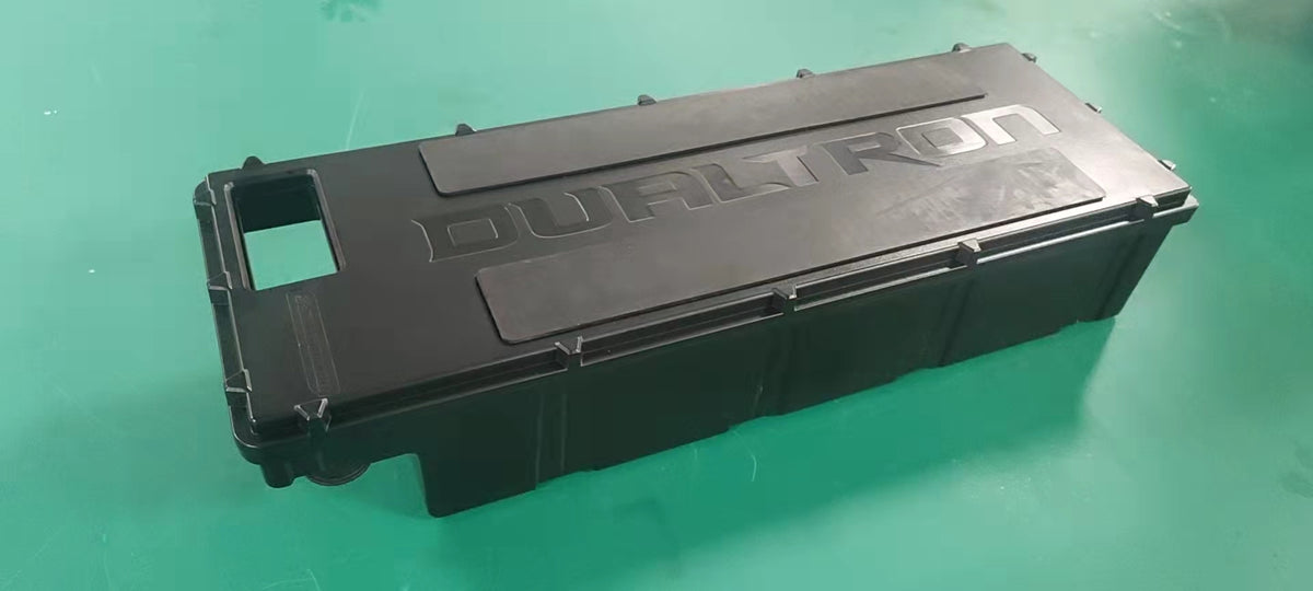 Pack batterie noir 60V 22,5Ah marqué Dualtron posé sur une surface verte