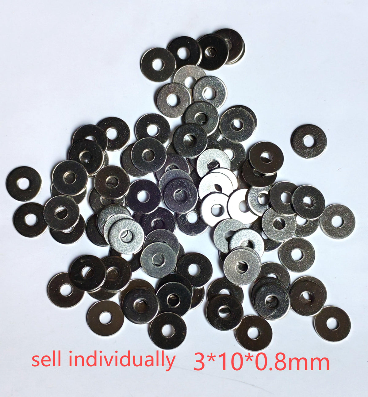 Rondelles métalliques plates M3x10x0,8 mm posées en vrac sur un fond blanc