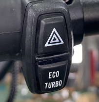 Commodo double fonction noir fixé sur un guidon avec boutons feux de détresse et Eco Turbo