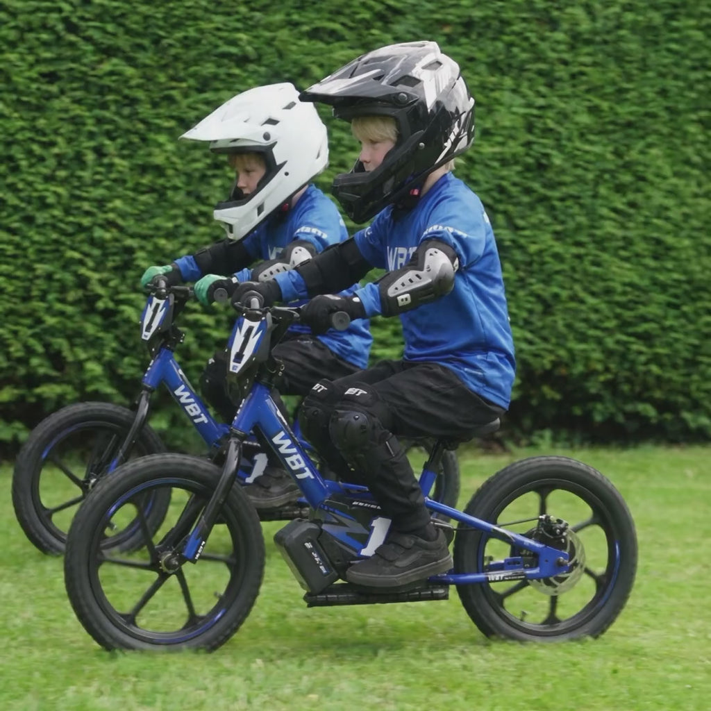 Deux enfants côte à côte lancent leurs draisiennes électriques WBT dans le jardin